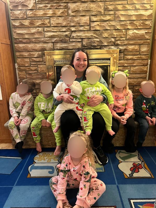 Woman surrounded by kids in festive pajamas.
