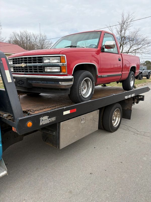 Red Chevrolet pickup truck on a flatbed tow truck.