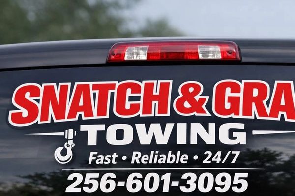 Snatch & Grab Towing company logo with contact number on vehicle window.