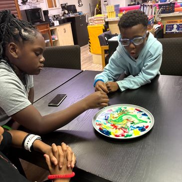 Two kids experimenting with colors on a plate.