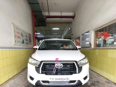 White Toyota Crysta parked indoors with decorative ribbons.