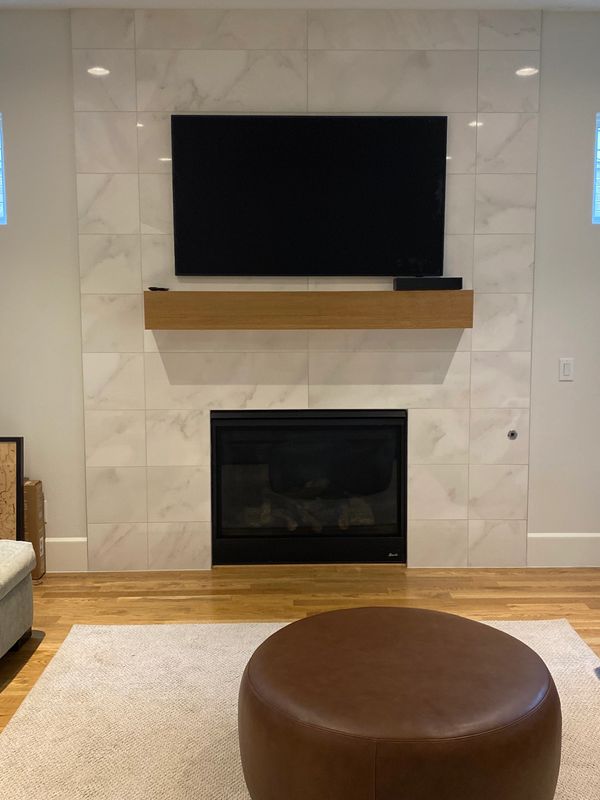 TV mounted on tile surface over fireplace.