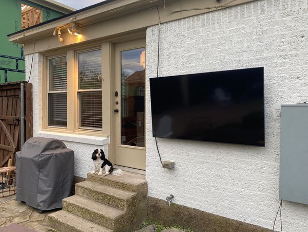 TV mounted on outside wall in the backyard.