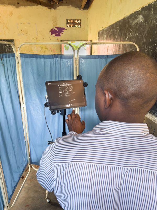 Man using a tablet with ultrasound images in a medical setting.