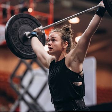 Female CrossFit athlete lifting a heavy barbell overhead.