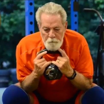 A determined senior man doing a kettlebell squat workout.