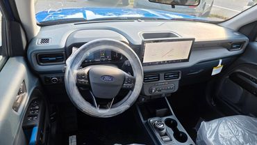 Interior view of a new Ford vehicle with a plastic-wrapped steering wheel and digital display.