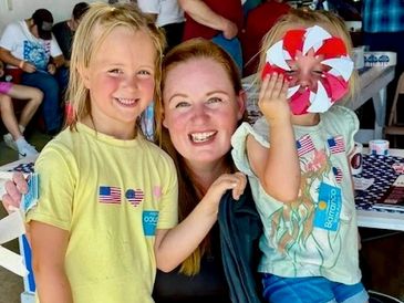 Smiling mother with two kids at a festive event.