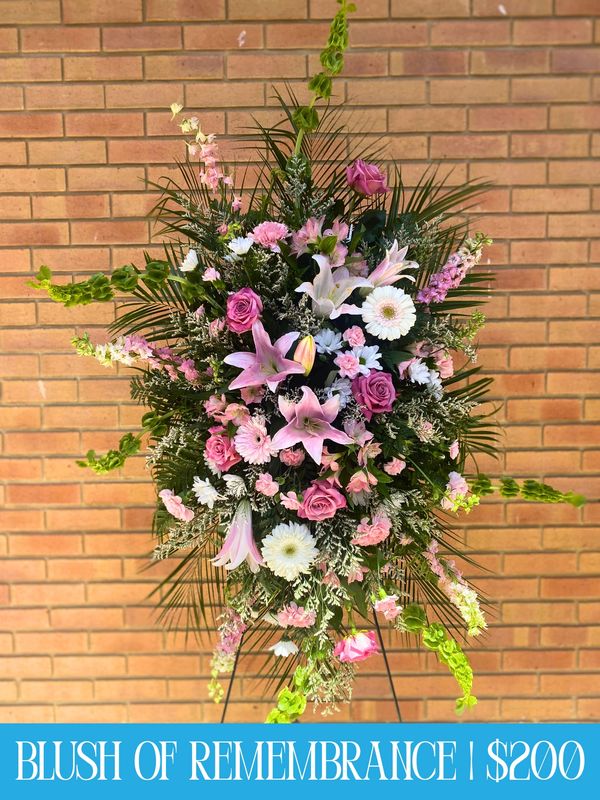 Elegant floral arrangement with pink, white flowers and greenery on a stand.