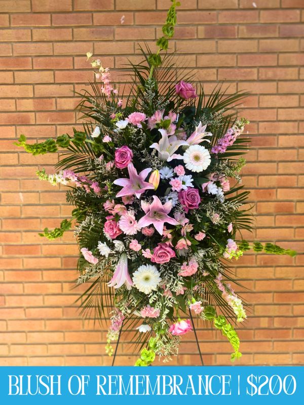 Elegant floral arrangement with pink, white flowers and greenery on a stand.