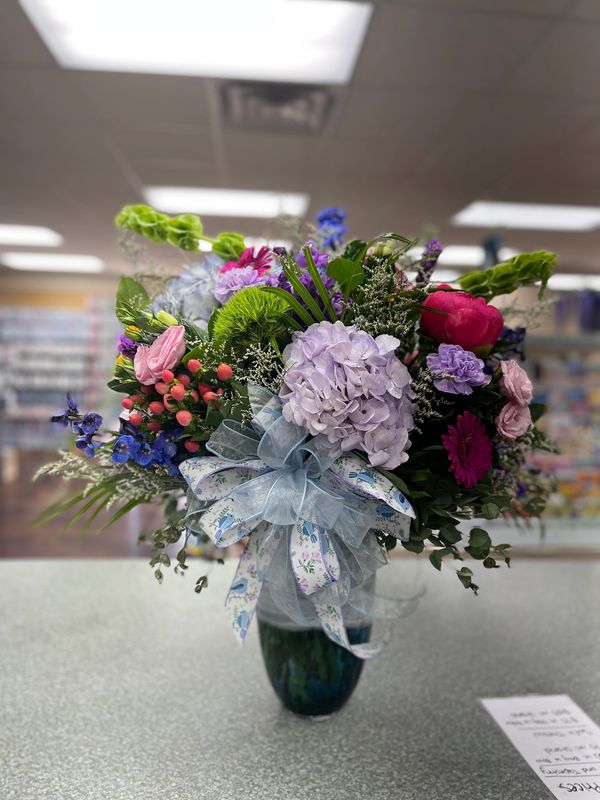 Colorful flower bouquet with a decorative blue ribbon in a vase.