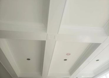 White coffered ceiling with recessed lighting.