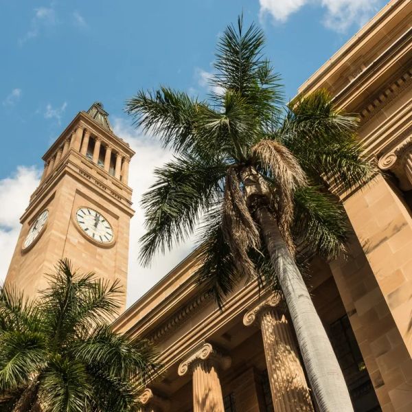 Clock tower and palm trees under blue sky.