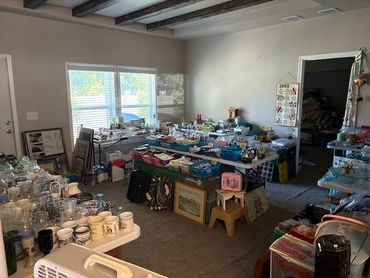 Room filled with tables of assorted household items for sale.