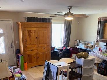 Living room cluttered with furniture, household items, and storage containers.