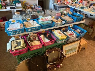 Table with baskets of linens and vintage household items for sale.