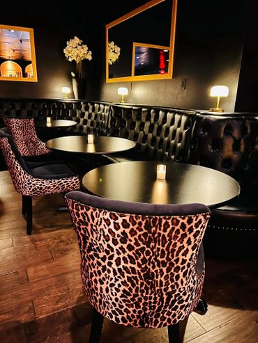 Cozy bar seating with leopard print chairs and dim candlelight.