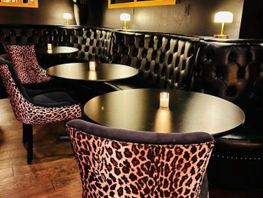 Cozy bar seating with leopard print chairs and dim candlelight.