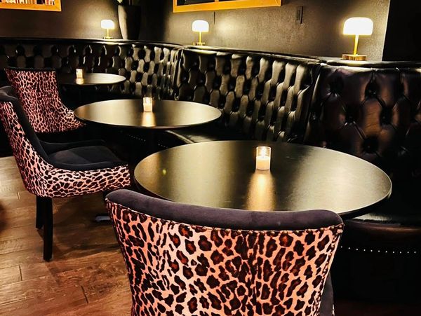 Cozy bar seating with leopard print chairs and dim candlelight.