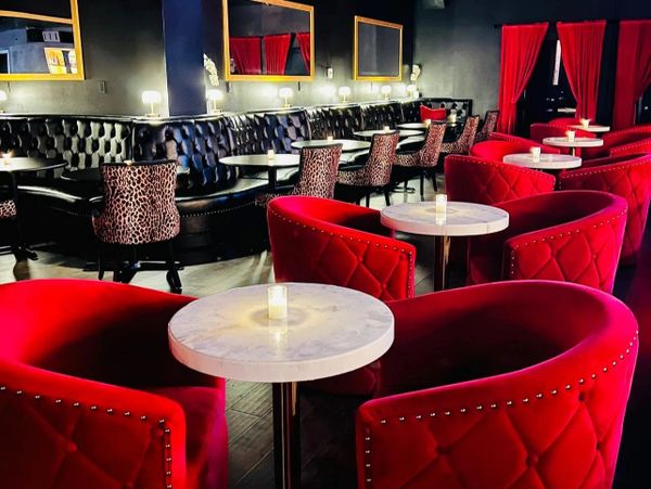 Luxurious lounge with red velvet chairs and intimate round tables.