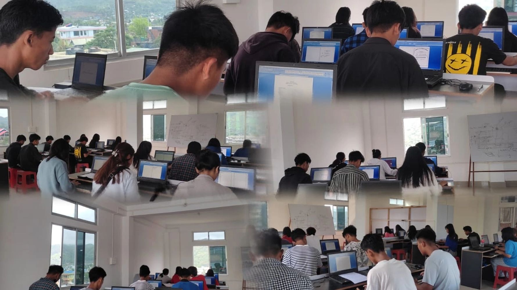 Students working on laptops in a classroom with large windows and whiteboard.