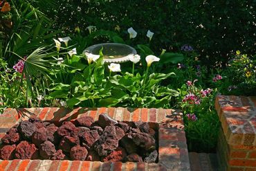 Built in gas fire feature with red lava rocks using brick surround. Tropical Southern California tra
