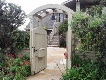 wood Arched entryway with lantern, wood gate, and archway with Flagstone and craftsman style home. S