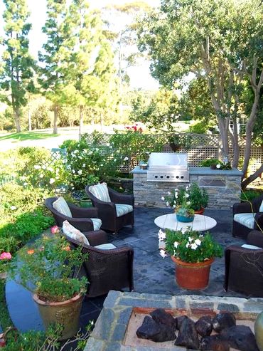 Stone Patio, outdoor kitchen, flowerbeds roses, cozy sitting area, trees, grass, potted flowers,