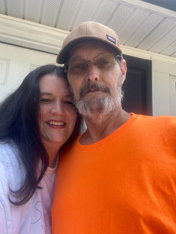Couple posing for a selfie outside their home.
