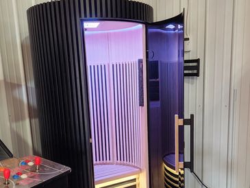 Modern infrared sauna cabin with purple lighting and wooden interior.
