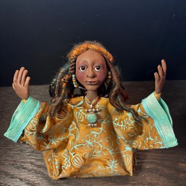 Handcrafted doll with raised arms and colorful attire.