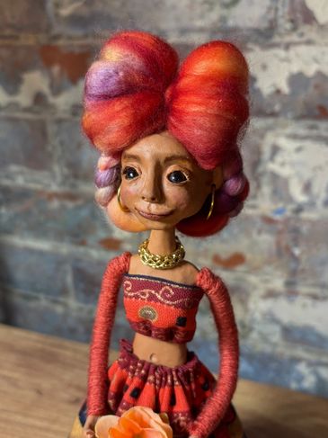Art doll with vibrant red and purple hair and colorful outfit.