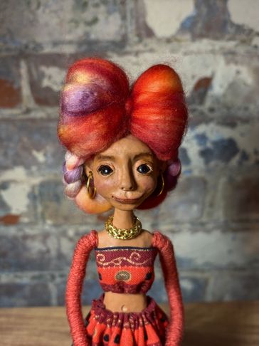 Handcrafted doll with vibrant hair and detailed clothing.