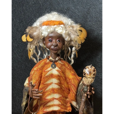 Handcrafted doll with feathers and intricate clothing.