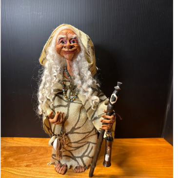 Handcrafted figurine of an old woman with curly white hair and a staff.