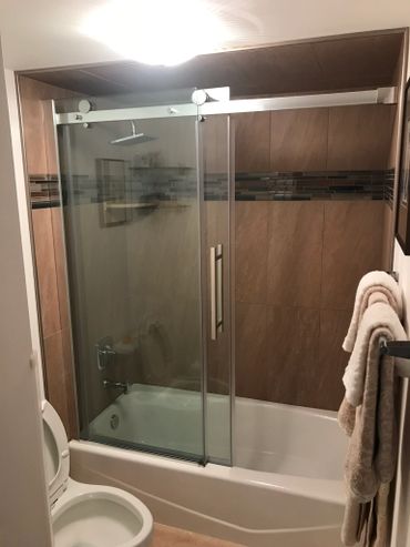 Modern bathroom with glass shower doors and beige tiles.