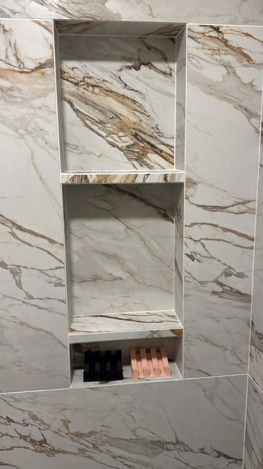 Marble wall with built-in shelves and two soap holders at the bottom.