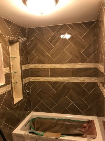 Bathroom with brown tiled walls and a bathtub under construction.