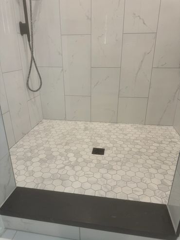 Modern shower with hexagonal floor tiles and large rectangular wall tiles.