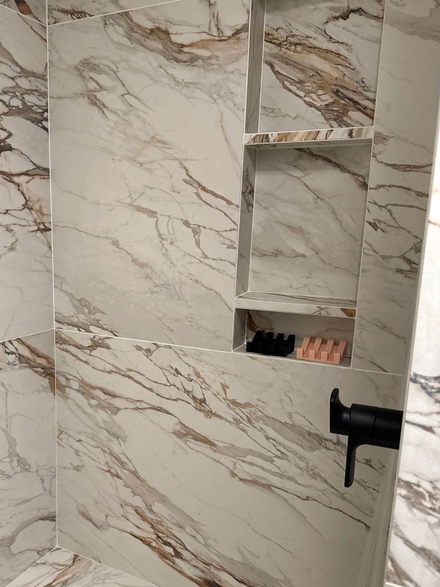 Marble shower corner with built-in shelves and bench.