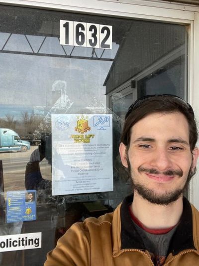 Smiling man taking a selfie in front of a glass door with address 1632.