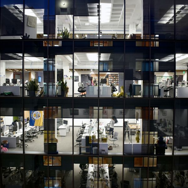 Modern office building with illuminated workspaces at night.