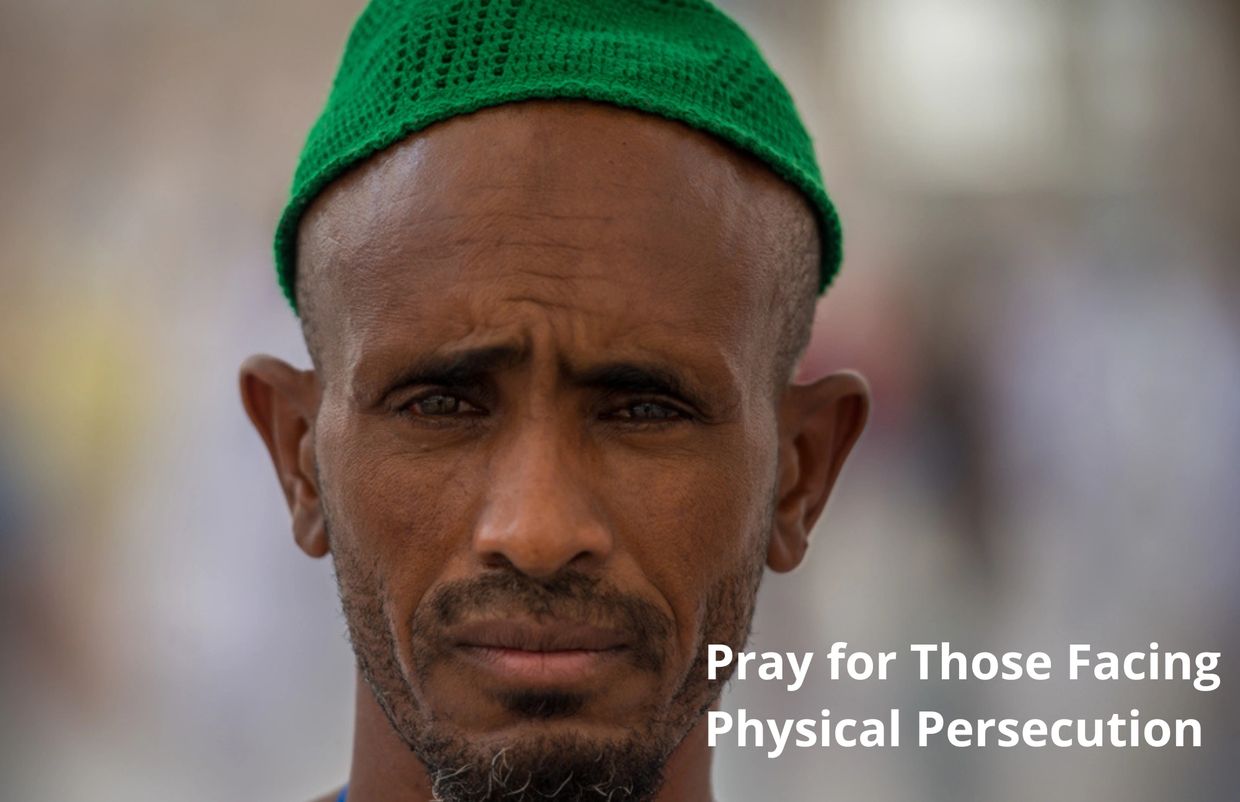 Portrait of a man in a green cap with a serious expression, urging prayers for those facing persecution.