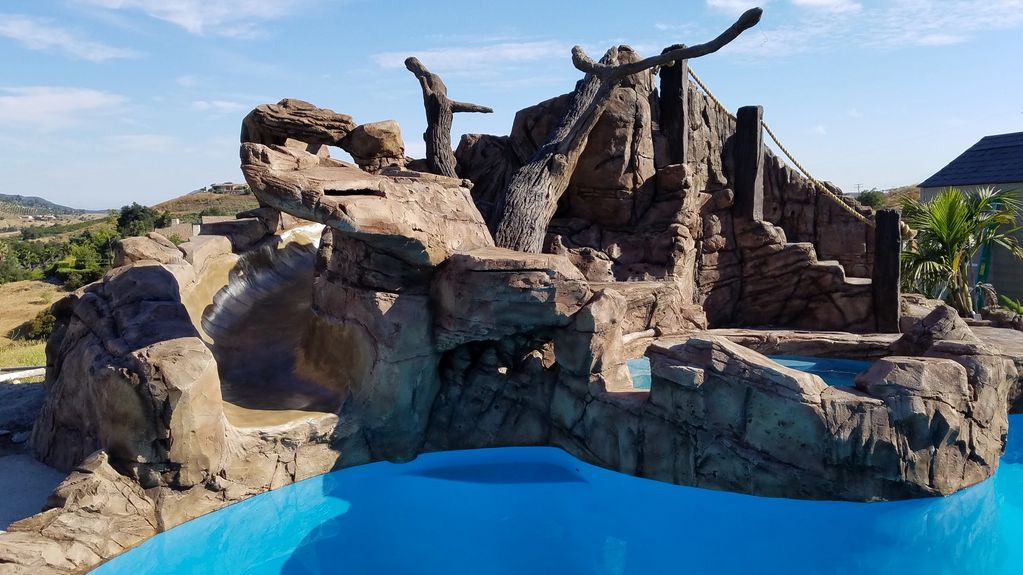 Rock-themed water slide in a pool area.