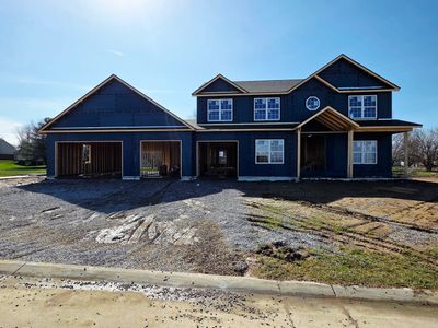 Newly constructed two-story house with dark blue exterior and unfinished driveway.