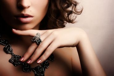 Close-up of a woman with elegant jewelry and manicured nails.