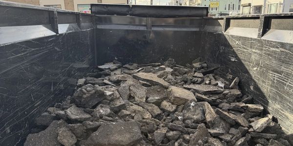 A truck bed filled with broken asphalt pieces.