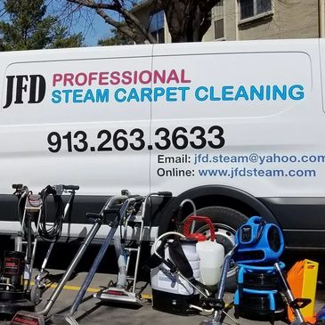 Professional steam carpet cleaning equipment in front of a service van.