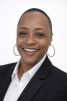 Smiling professional woman in a black blazer and hoop earrings.