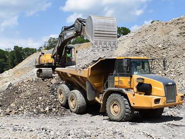Yellow dump truck loading gravel.